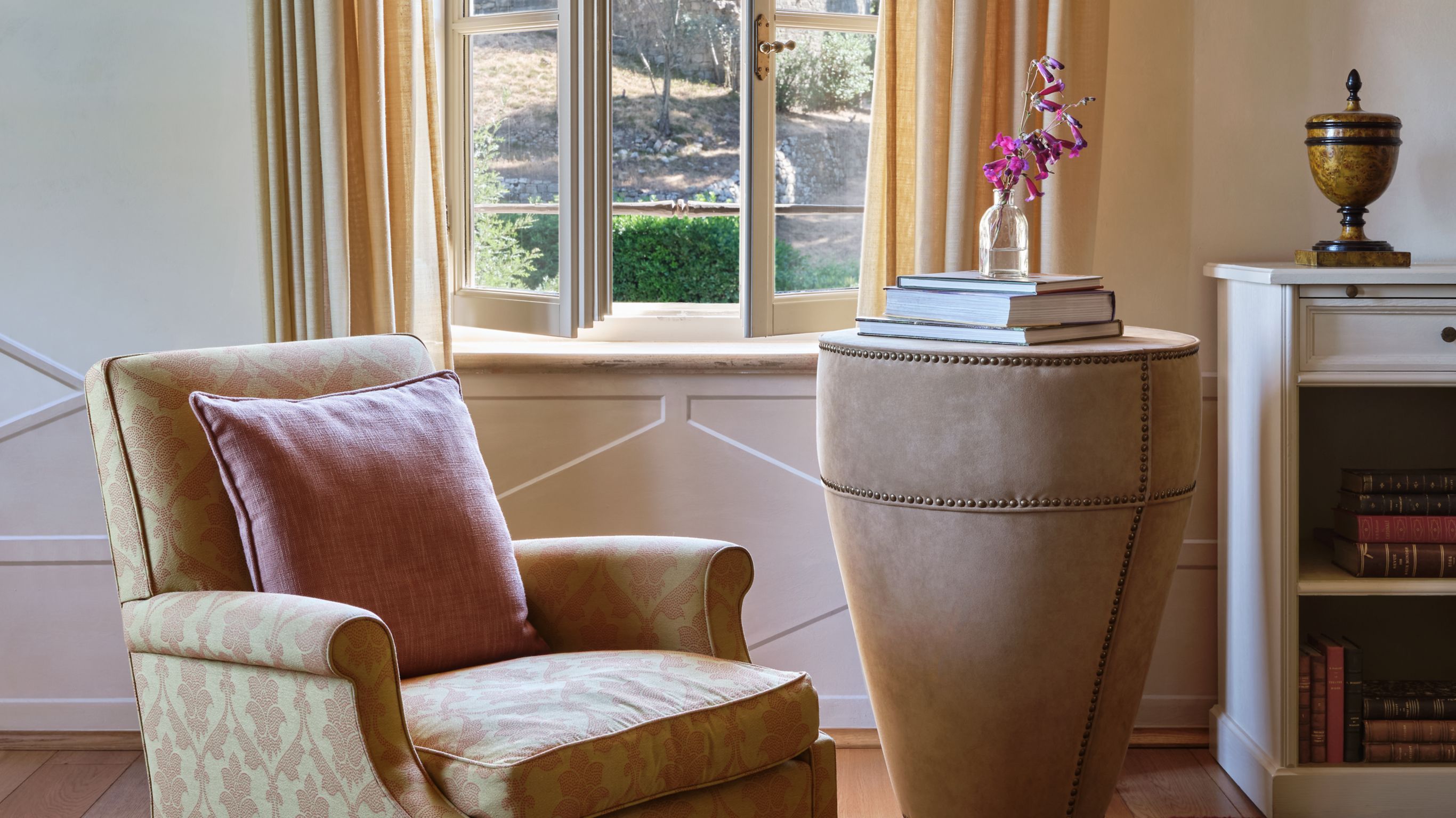 Reading nook with armchair, side table,  books, and a window view